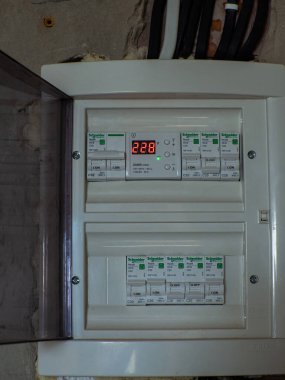 Ivano-Frankivsk, Ukrayna, 11 Haziran 2023: Dijital ekran sayaçlarının yer aldığı beyaz plastik panel. Boş modern bir evde, elektrik bağlantı kutusu ve kablo bağlantılarını ortaya çıkarıyor..