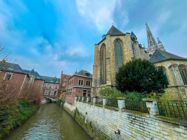 Leuven 'deki tarihi kasaba evleriyle yan yana duran ve berrak mavi gökyüzünün altında akan sakin bir kanalla tamamlanan gotik bir kilisenin manzarası, şehirlerin zengin mimari mirasını gözler önüne seriyor..