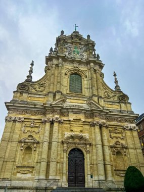 Bu görüntü, Leuven 'deki barok bir kilisenin çarpıcı bir ön görüntüsünü yakalıyor. Karmaşık taş cephesini, ön kapıya uzanan görkemli merdivenlerini ve parlak mavi gökyüzünü gösteriyor..