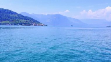 İtalya 'daki mavi gökyüzünü yansıtan sakin bir Iseo gölünün olduğu çarpıcı bir manzara. Yeşillik tarafından çerçevelenmiş görkemli dağlar uzaklardan yükselir. Huzurlu ve görkemli bir manzara yaratır..