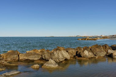Deniz sahilini koruyan doğal bir dalgakıran oluşturan bir kayalık şeridi.