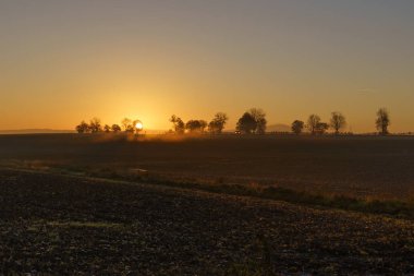 Beautiful sunrise over the mountains in the area of still shaded farmland