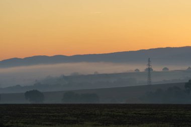 Beautiful sunrise over the mountains in the area of still shaded farmland