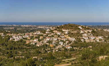 Arka planda deniz ve ormanın olduğu uzak bir kasabaya bakan güzel bir manzara.