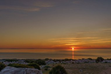 Sicilya 'yı ve kayalık kıyılarını çevreleyen cam sahilde güzel bir gün batımı..