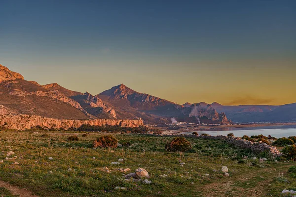 Kayalık dağ zirvelerinin ve duvarların indiği ılık denizin üzerinde güzel bir günbatımı..