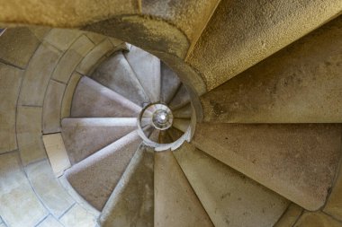 Eski bir binadaki eski, dar, yuvarlak bir merdiven.