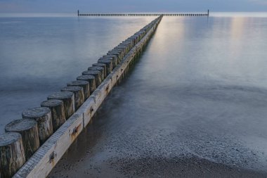 Deniz ufkunda gün batımı. Bulanık dalgalar kıyıda ve dalgalar arka planda.