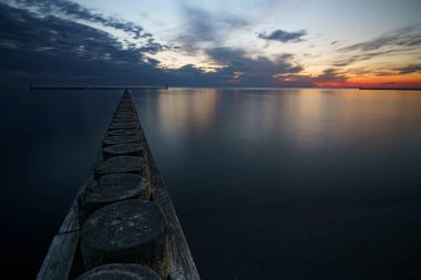 Deniz ufkunda gün batımı. Bulanık dalgalar kıyıda ve dalgalar arka planda.