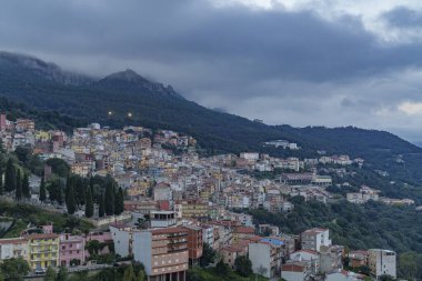 Gökyüzü bulutlu, ormanın ortasında gizlenmiş, çok yoğun inşa edilmiş bir kasabanın manzarası..