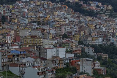 Gökyüzü bulutlu, ormanın ortasında gizlenmiş, çok yoğun inşa edilmiş bir kasabanın manzarası..