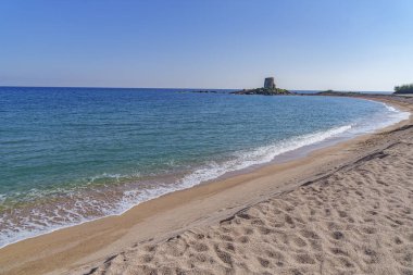 Önünde eski bir tuğla kulesi ve güzel bir plajı olan güzel bir sahil.