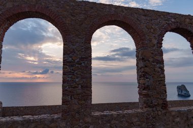 Gün batımında eski tuğla pencerelerden denize bak.