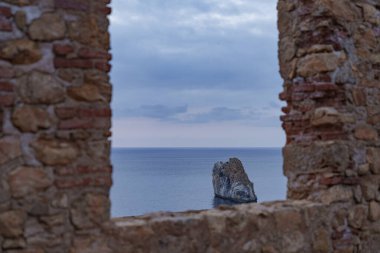 Gün batımında eski tuğla pencerelerden denize bak.