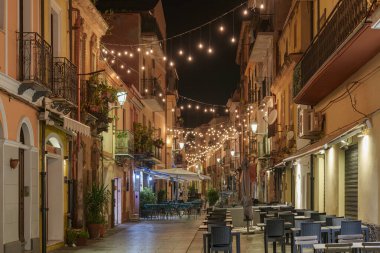 Geceleri eski binaların olduğu boş, güzel aydınlatılmış bir cadde manzarası..