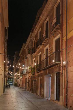 Geceleri eski binaların olduğu boş, güzel aydınlatılmış bir cadde manzarası..
