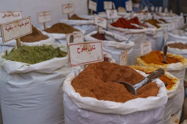 Arap dilinde tarif edilen küçük bir şehir pazarında büyük miktarlarda satılan renkli baharatlar..