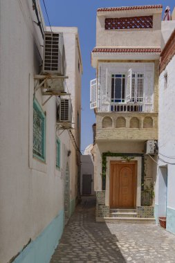 Eski beyaz evleri ve renkli sonları olan dar Tunus sokakları.