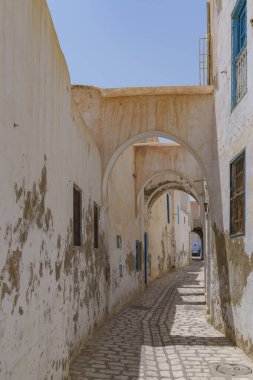 Tuğla kemerlerle kaplı dar Tunus sokakları gölgeler oluşturuyor