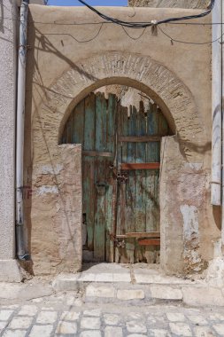 Çok eski, harap ve çökmüş eski ağaçlarla dolu bir bina cephesi.