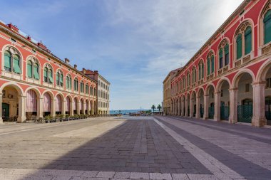 Denizin kenarında yenilenmiş eski binalarla çevrili taş döşenmiş güzel bir meydan.