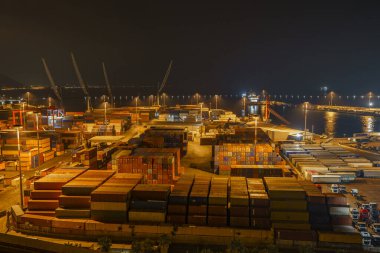 Konteynırların saklandığı büyük bir endüstriyel limanın gece panoraması.