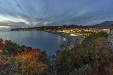 Deniz kenarına inşa edilmiş güzel, renkli bir şehrin gece manzarası.