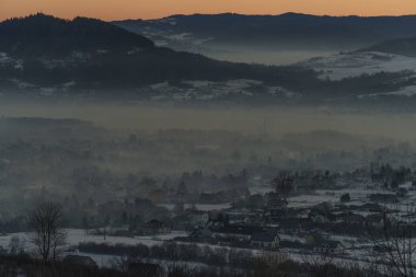 Güneşin doğuşuyla birlikte kışın sisli manzaralı köy evlerinin olduğu sisli bir dağ vadisinin sabah manzarası..