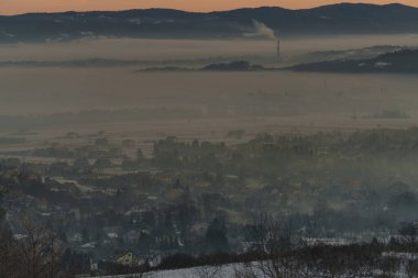 Güneşin doğuşuyla birlikte kışın sisli manzaralı köy evlerinin olduğu sisli bir dağ vadisinin sabah manzarası..