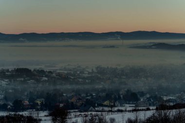 Güneşin doğuşuyla birlikte kışın sisli manzaralı köy evlerinin olduğu sisli bir dağ vadisinin sabah manzarası..
