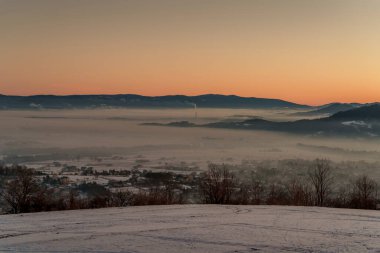 Güneşin doğuşuyla birlikte kışın sisli manzaralı köy evlerinin olduğu sisli bir dağ vadisinin sabah manzarası..
