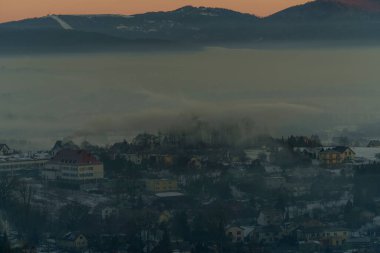 Güneşin doğuşuyla birlikte kışın sisli manzaralı köy evlerinin olduğu sisli bir dağ vadisinin sabah manzarası..