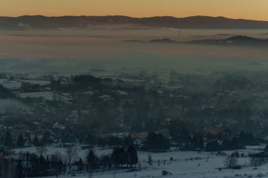 Güneşin doğuşuyla birlikte kışın sisli manzaralı köy evlerinin olduğu sisli bir dağ vadisinin sabah manzarası..