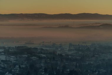 Güneşin doğuşuyla birlikte kışın sisli manzaralı köy evlerinin olduğu sisli bir dağ vadisinin sabah manzarası..
