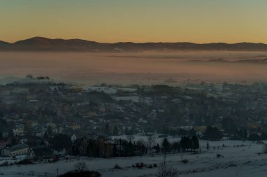 Güneşin doğuşuyla birlikte kışın sisli manzaralı köy evlerinin olduğu sisli bir dağ vadisinin sabah manzarası..