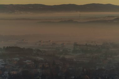 Güneşin doğuşuyla birlikte kışın sisli manzaralı köy evlerinin olduğu sisli bir dağ vadisinin sabah manzarası..
