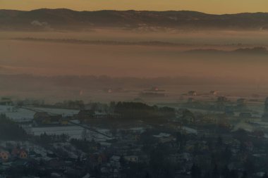 Güneşin doğuşuyla birlikte kışın sisli manzaralı köy evlerinin olduğu sisli bir dağ vadisinin sabah manzarası..