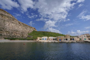 Yeşil yamaçlı ve bulutlu kayık sığınakları uçurum kenarında sakin bir körfez çiziyor..