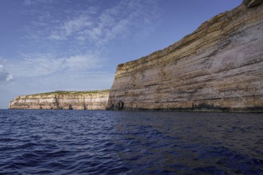 Uzun katmanlı kireçtaşından oluşmuş burunlar alacakaranlıkta dalgalı Akdeniz sularının üzerinde yükselir..