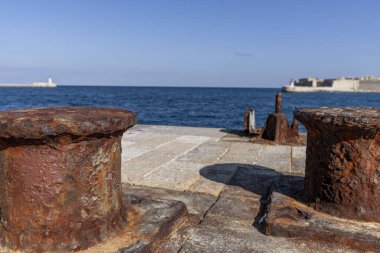 Engin okyanus ve arka planda kaleyle taş iskeledeki yıpranmış demirleme direklerine yakın çekim..
