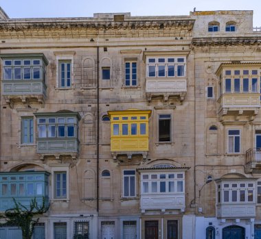Malta 'daki tarihi binada taş işçiliği ve çeşitli pastel renkli ahşap kaplamalı balkonlar yer alıyor..