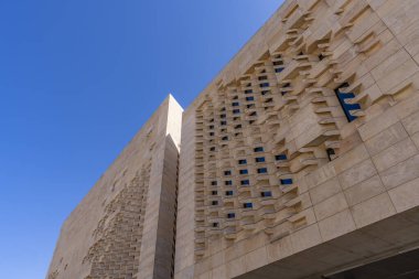 Ditch and massive bastion of Vallettas city fortifications iconic limestone walls and restored dry moat garden beneath clear Mediterranean sky.
