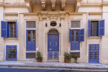 Elegant historic entrance features carved pediment, arched fanlights and matching blue doors and shutters framed by pilasters.