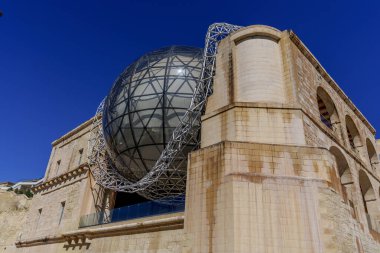 Striking architectural contrast of glass domed sphere and steel lattice attached to historic stone building.