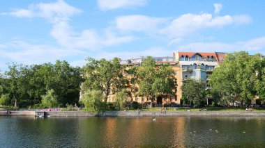 Berlin, Almanya, 11 Temmuz 2023, Landwehrkanal üzerinde Urbanhafen 'den Fraenkelufer, Kreuzberg' e yerleşim binaları ve ağaçlarıyla