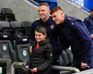 Blackpool 'dan Shayne Lavery # 19 ve Sonny Carey, 12 Kasım 202' de İngiltere 'nin Wigan Stadyumu' nda oynanan Sky Bet Şampiyonası maçından önce genç bir hayranla poz verdiler.