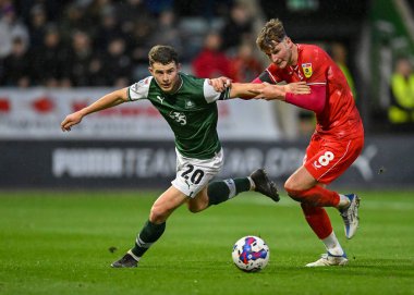 Plymouth Argyle orta saha oyuncusu Adam Randell (20) topu Milton Keynes Dons orta saha oyuncusu Ethan Robson 'dan (8) koruyor. Plymouth Argyle, Home Park, Plymouth, İngiltere 1 Ocak' ta MK Dons 'a karşı oynadığı maçta faul yaptı.