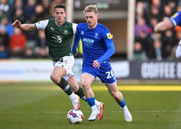 Cheltenham Town midfielder Taylor Perry  (28) shields the ball from Plymouth Argyle midfielder Jordan Houghton  (4)  during the Sky Bet League 1 match Plymouth Argyle vs Cheltenham Town at Home Park, Plymouth, United Kingdom, 21st January 202