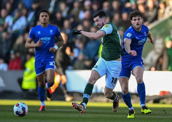 Plymouth Argyle midfielder Finn Azaz (18) passes the ball forward while under pressure from Cheltenham Town defender Charlie Raglan  (5)  during the Sky Bet League 1 match Plymouth Argyle vs Cheltenham Town at Home Park, Plymouth, United Kingdom, 21s