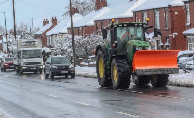 Şiddetli kar yağışı Barnsley 'i vururken bir traktör kar küreme aracı yolda. Sarı kar uyarısı Yorkshire bölgesinde uygulanırken; Barnsley, Güney Yorkshire, İngiltere, 10 Mart 2023